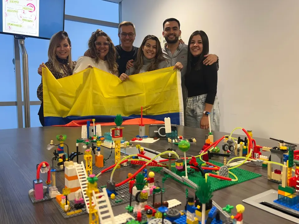 Equipo celebrando con una bandera de Colombia junto a la maqueta que construyó en un taller